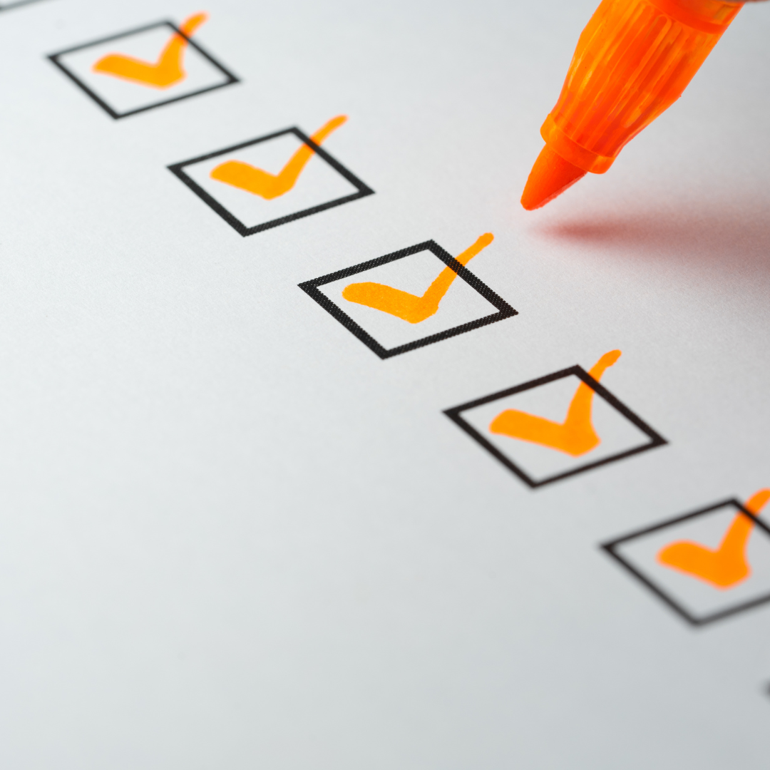 Orangefarbener Stift markiert mehrere Kästchen mit Häkchen auf einer Checkliste.